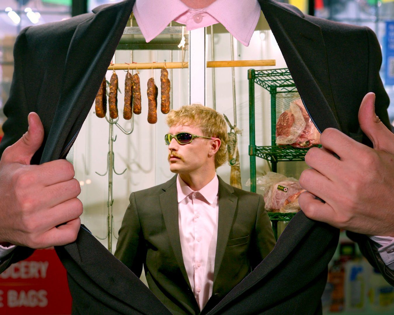 Chace Cade in a green suit and sunglasses opening his jacket